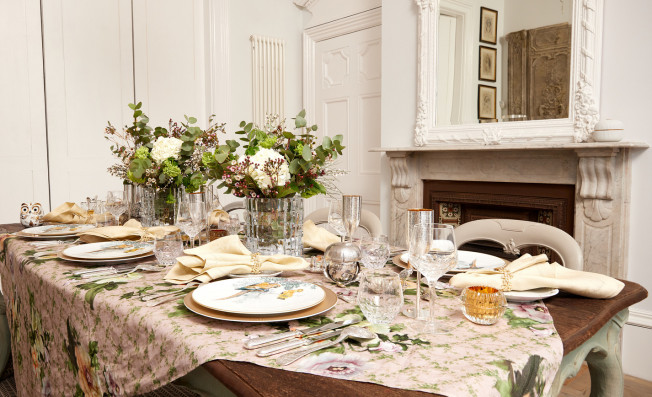 lavish dinner on a wooden table and plates, flowers, wine glasses and forks rested on the table